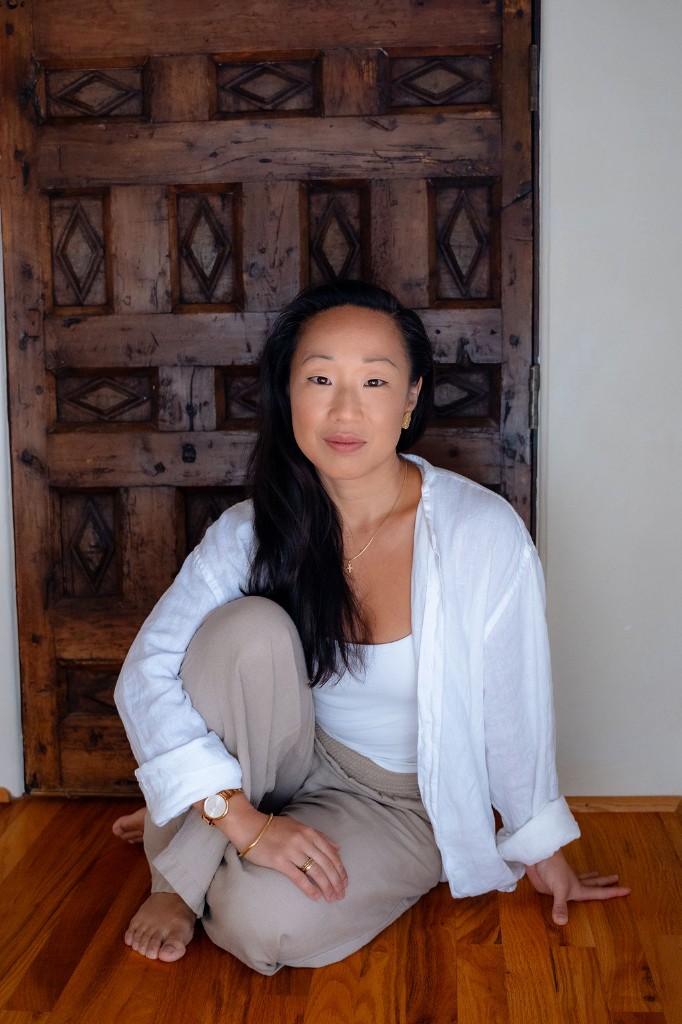 Victoria Grace seated on a wooden floor in front of a carved studio door